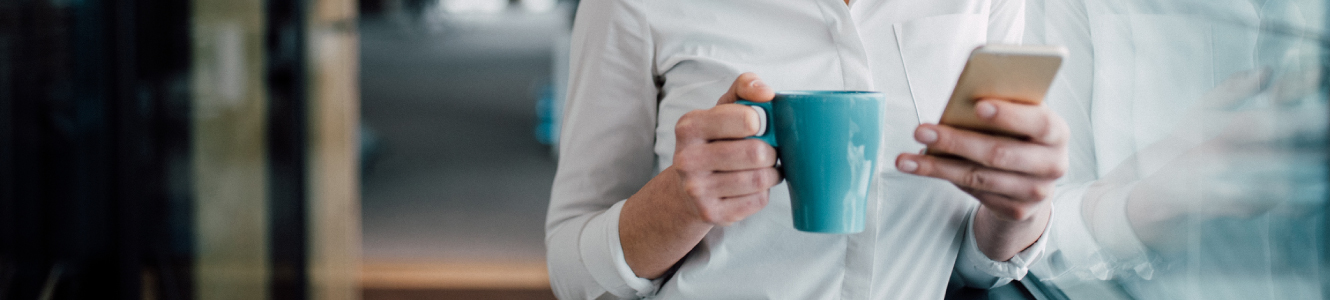 Woman with coffee looking at mobile phone