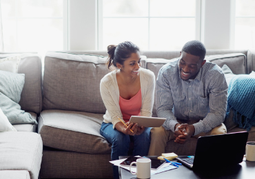 Young couple using tablet device on couch