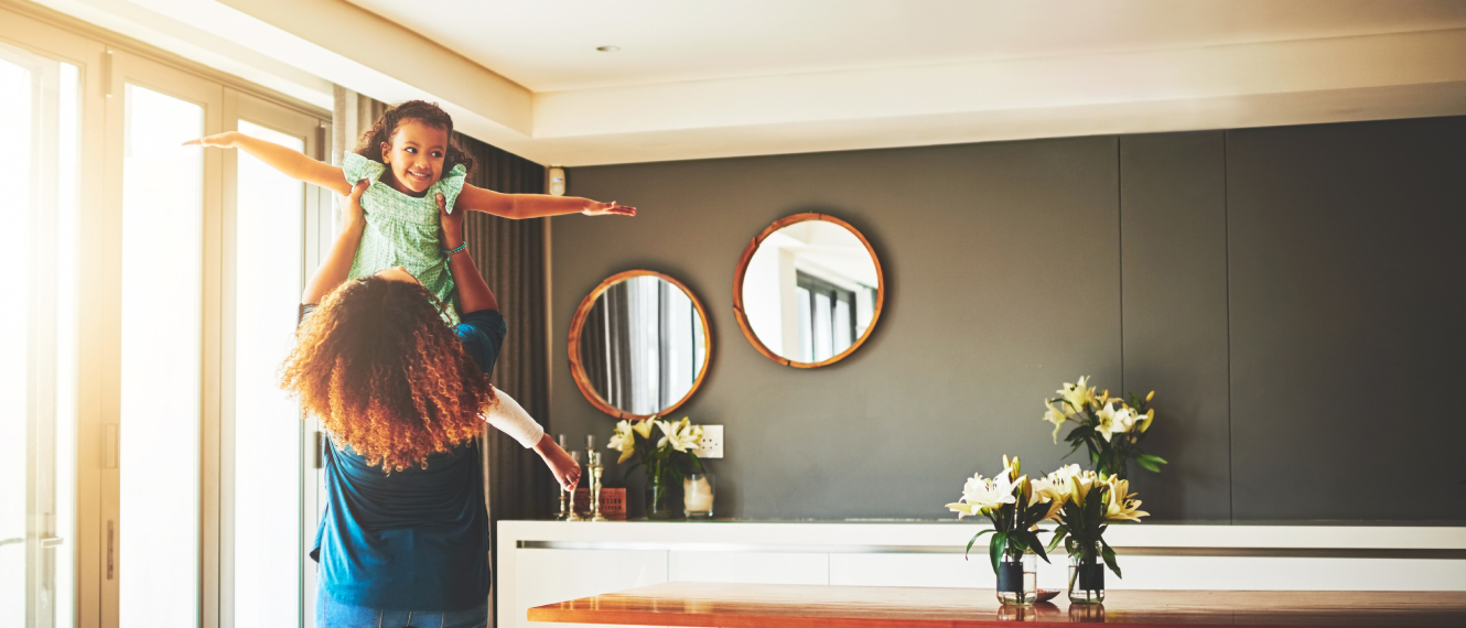 Mother holding up daughter in living room