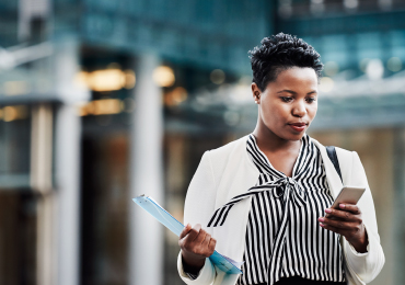 A businesswoman using mobile phone while walking